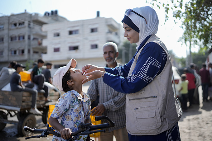 A woman gives an oral polio vaccine to a young boy.