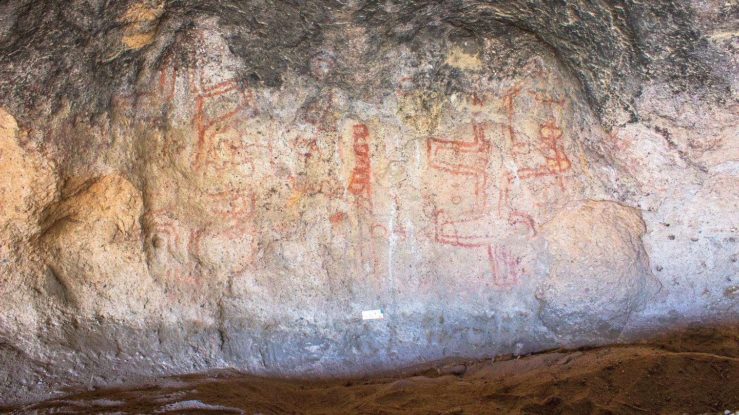 A cave wall in Patagonia is covered with pictures of several large figures and shapes made of some kind of red cartoon material. Some of the art in this cave dates back as far as 8,200 years ago.